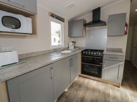A kitchen with various appliances and cabinets at Gold Caravan (203) Talybont