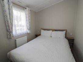A bedroom with a bed and a window at Gold Caravan (203) Talybont