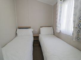 A bedroom with two single beds and a window at Gold Caravan (203) Talybont