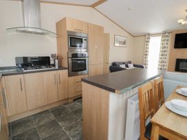 A kitchen with appliances and dining area at Gold Lodge (201) Talybont