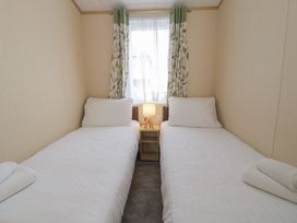 A bedroom with two single beds and a lamp on a nightstand at Gold Lodge (201) Talybont