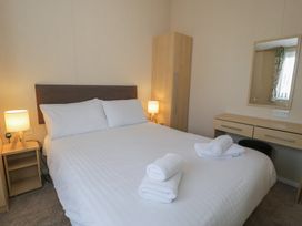 A bedroom with a bed and nightstand at Gold Lodge (201) Talybont