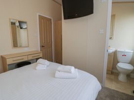 A bedroom with a bed and a mirror at Gold Lodge (201) Talybont