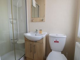 A bathroom with a sink, toilet, shower, and mirror at Gold Lodge (201) Talybont