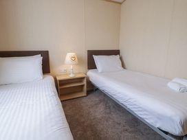 A bedroom with two single beds and a nightstand at Gold Lodge (201) Talybont