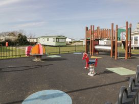 A playground with equipment including a slide and spring riders at Gold Lodge (201) Talybont