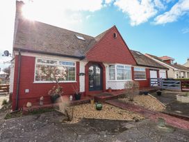 Front exterior of a red and white house with plants in pots and a gravel garden at Bryn-Y-Glyn in Penrhyn Bay