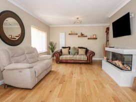 A living room with two sofas a wall mounted tv a fireplace and wooden flooring at Bryn-Y-Glyn in Penrhyn Bay