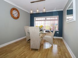 A dining room with a round glass table four chairs and a wall clock at Bryn-Y-Glyn Penrhyn Bay