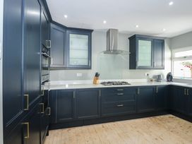 A kitchen with blue cabinets a gas stove a knife block and appliances on counters at Bryn-Y-Glyn in Penrhyn Bay