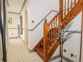 A hallway with a wooden staircase and patterned floor tiles at Bryn-Y-Glyn in Penrhyn Bay