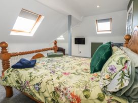 A bedroom with a wooden bed a TV on the wall two skylight windows and folded towels on the bed at Bryn-Y-Glyn in Penrhyn Bay