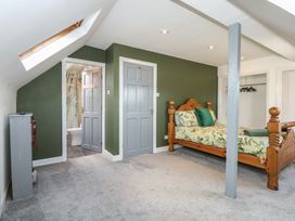 A bedroom with a wooden bed with floral bedding green wall skylight two gray doors and an open closet at Bryn-Y-Glyn in Penrhyn Bay