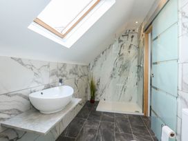 A bathroom with a sink, a walk-in shower, a skylight, and a frosted glass door at Bryn-Y-Glyn in Penrhyn Bay
