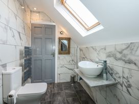 A bathroom with a toilet sink mirror skylight and gray tiled floor at Bryn-Y-Glyn in Penrhyn Bay