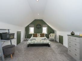 A bedroom with a bed chair dresser and shelves in an attic space at Bryn-Y-Glyn in Penrhyn Bay