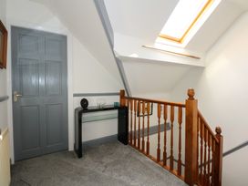 A hallway with a gray door a black console table wooden stair railing and a skylight at Bryn-Y-Glyn in Penrhyn Bay