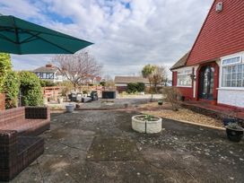 A patio area with outdoor seating and potted plants beside a house with a red and white exterior at Bryn-Y-Glyn in Penrhyn Bay