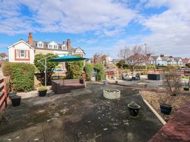 An outdoor patio area with garden furniture plants and a blue umbrella in a residential neighborhood at Bryn-Y-Glyn in Penrhyn Bay
