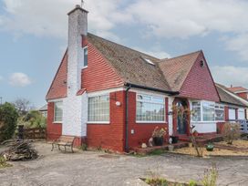 A red brick and white stucco house with multiple windows and a chimney on a paved driveway at Bryn-Y-Glyn in Penrhyn Bay