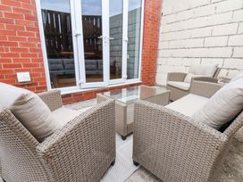 A patio area with four chairs and a glass table at Falcon's Nest in Whitby