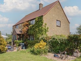 A stone house with a tiled roof surrounded by plants and garden furniture at Yeabridge Farm in Mosterton near Beaminster