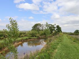 A river with trees and grass on the banks and a fenced grassy path at Yeabridge Farm in Mosterton near Beaminster
