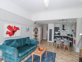 An open living room and kitchen area with a teal sofa a wooden coffee table and a dining table with gray chairs at Porto Brid in Bridlington