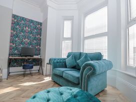 A sitting area with a teal sofa and ottoman near large windows and a desk with a computer at Porto Brid in Bridlington