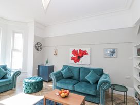 A living room with teal sofas a wooden coffee table and wall art at Porto Brid in Bridlington