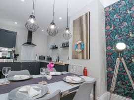 A dining area with a table set for four near a kitchen with dark cabinets and a floral patterned wall at Porto Brid in Bridlington