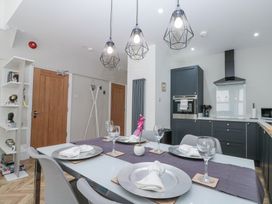 A dining table set with plates napkins and wine glasses in a kitchen with dark cabinets and pendant lights at Porto Brid in Bridlington