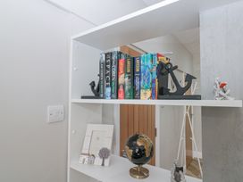 A white shelving unit with books held by anchor bookends and a decorative globe at Porto Brid in Bridlington