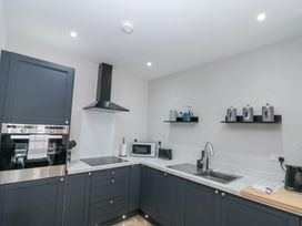 A kitchen with dark cabinets a built-in oven an electric cooktop a microwave toaster and a sink at Porto Brid in Bridlington