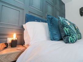 A bed with white bedding and blue decorative pillows next to a wooden nightstand with a lamp at Porto Brid in Bridlington