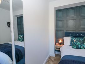 A bedroom with a bed white linens and blue pillows next to a wooden nightstand with a small lamp Porto Brid Bridlington