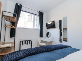 A bedroom with a bed a wall-mounted TV a dressing table with a mirror a chair and a clothing rack at Porto Brid in Bridlington