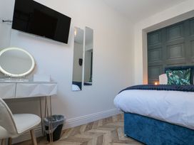 A bedroom with a bed a dressing table with a round mirror a chair and a wall mounted TV at Porto Brid in Bridlington