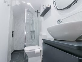 A bathroom with a toilet a shower with glass door a sink on a vanity and a wall shelf at Porto Brid in Bridlington