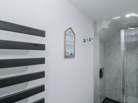 A bathroom with a glass shower cubicle tiled walls black towel radiator and a wall sign at Porto Brid in Bridlington