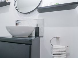 A bathroom sink with a round mirror soap dispenser and stacked towels on a towel ring at Porto Brid in Bridlington
