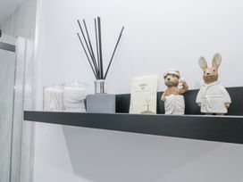 A black bathroom shelf with cotton swabs cotton pads a reed diffuser a shower cap and animal figurines at Porto Brid in Bridlington