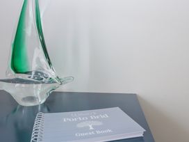 A glass sailboat sculpture and a guest book on a dark surface at Porto Brid in Bridlington