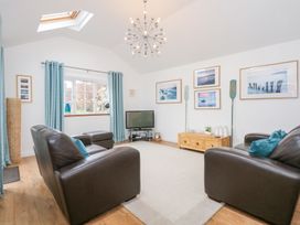 A living room with two brown leather sofas a TV on a stand blue curtains and framed pictures on the wall at Pippin Cottage in Beaumaris