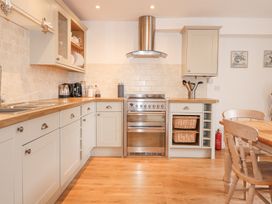 A kitchen with wooden countertops an oven and stovetop a sink coffee maker and dining table with chairs at Pippin Cottage in Beaumaris