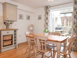 A dining area with wooden table and chairs next to an open patio door showing outdoor seating at Pippin Cottage in Beaumaris