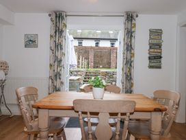 A dining room with a wooden table and chairs potted plant on table and open glass doors leading to an outdoor patio at Pippin Cottage in Beaumaris