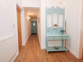 A hallway with a wooden floor and blue wooden console table with drawers at Pippin Cottage in Beaumaris