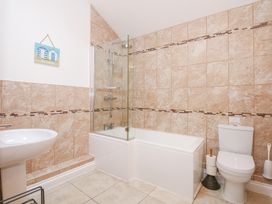 A bathroom with a bathtub and shower screen a toilet and a sink at Pippin Cottage in Beaumaris