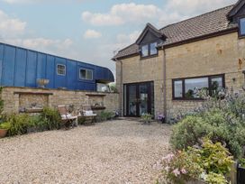 A gravel courtyard with outdoor chairs and plants next to a stone house at Pond View at Yeabridge Farm in Whetley Cross near Mosterton